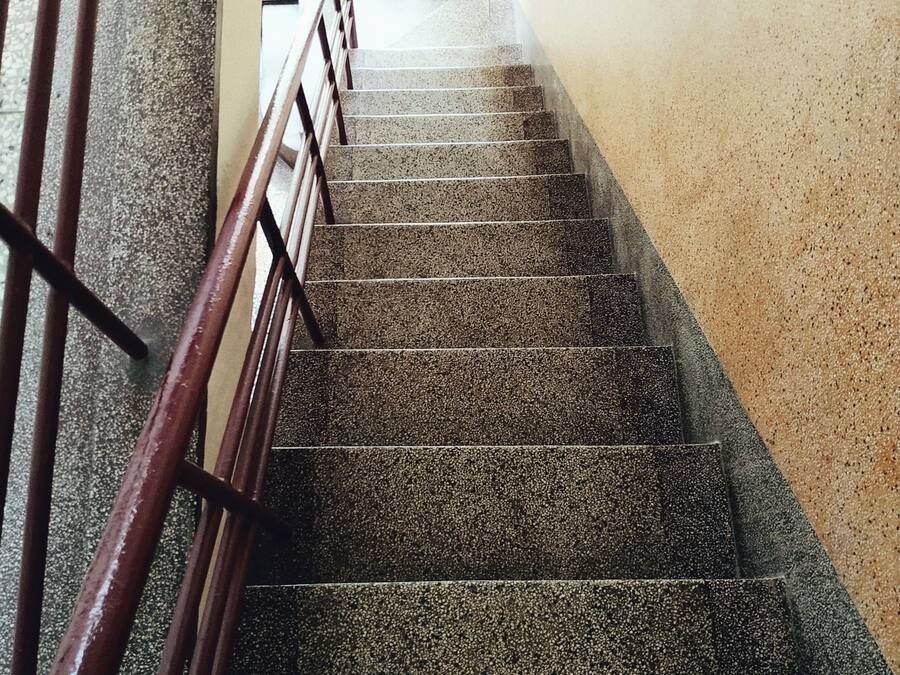 Una escalera con barandilla metálica que lleva a un espacio exterior.