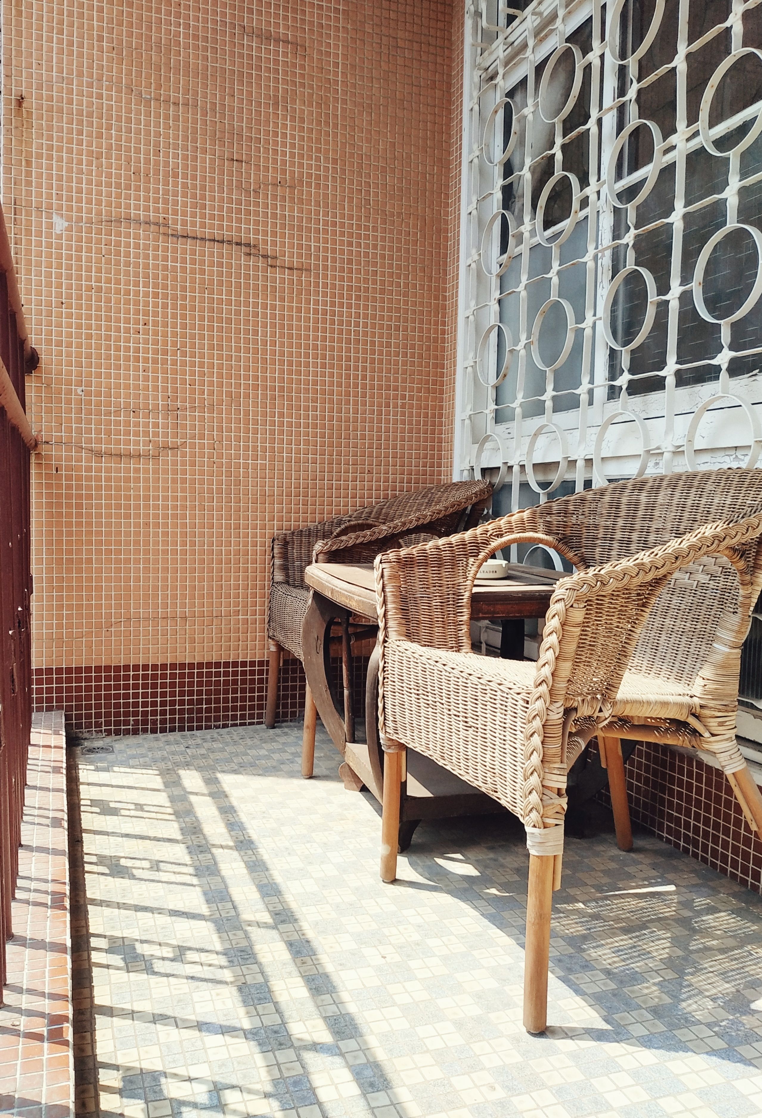 A patio area with wicker furniture and a tiled floor.