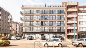 Een meerlaags woongebouw met balkons, een parkeerplaats met auto's, en een verkeersbord dat een zone van 30 meter aangeeft.
