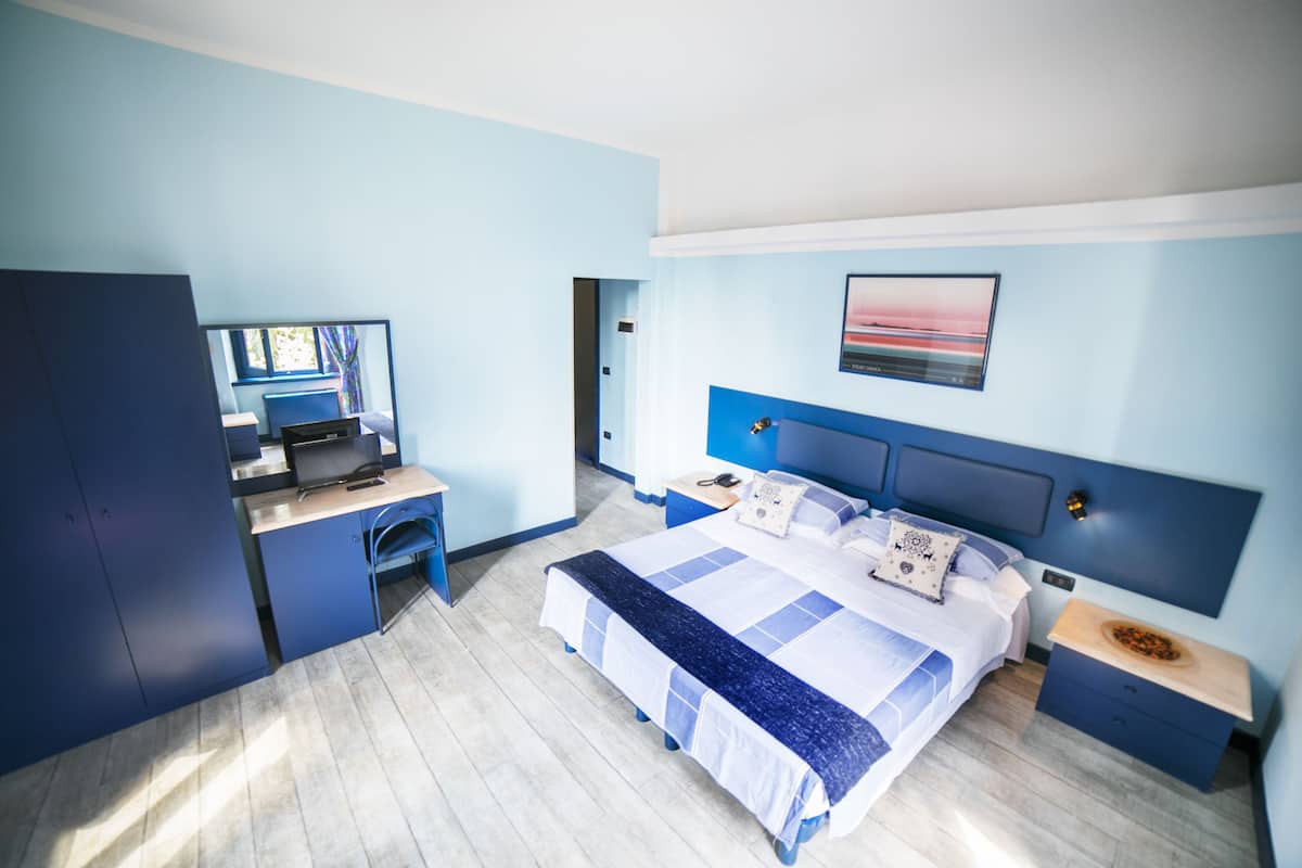 Ein modernes Hotelzimmer mit einem großen Bett, einem Schreibtisch und einem Kleiderschrank.