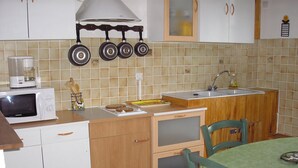 Une cuisine compacte équipée d’un four à micro-ondes, d’une cuisinière, d’un évier et de casseroles suspendues.