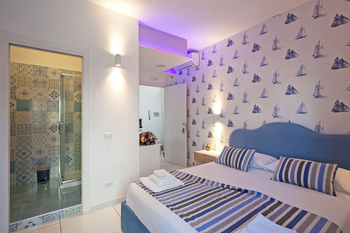 Ein Schlafzimmer mit einem Bett, einem Nachttisch, einem Spiegel und einer Wand mit Muster.