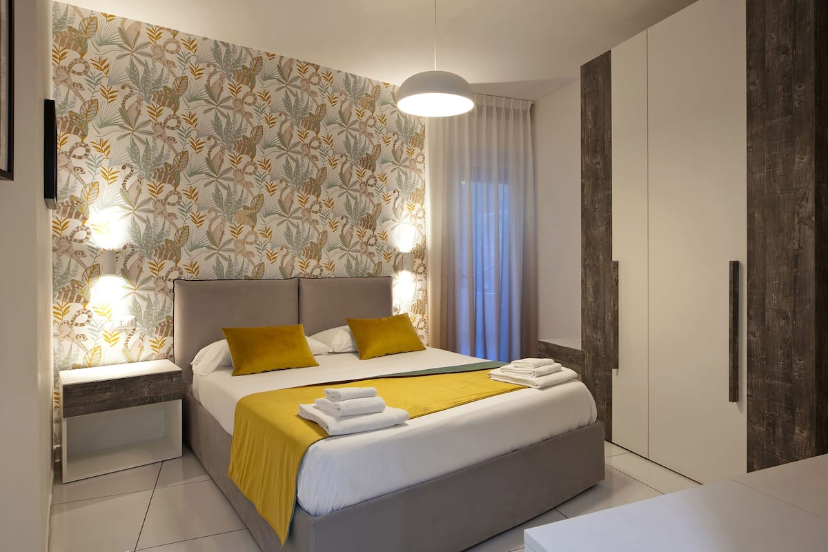 Ein modernes Schlafzimmer mit Bett, Nachttischen, einem Kleiderschrank und strukturierter Tapete.