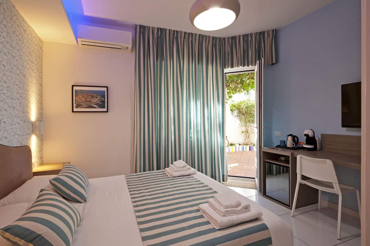 Ein Hotelzimmer mit Bett, Schreibtisch, Stuhl, Fernseher und einem Fenster mit Vorhängen.
