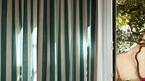 A view through a window with vertical stripes, a tree, and a wall with a curved design. - Maison Nonna Anna (Sorrento)