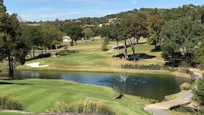 A golf course with a pond, trees, and a clear sky.