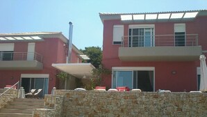 Un bâtiment à deux étages, avec un mur de pierre à l’avant, un escalier menant à l’entrée et un vélo garé près du mur.