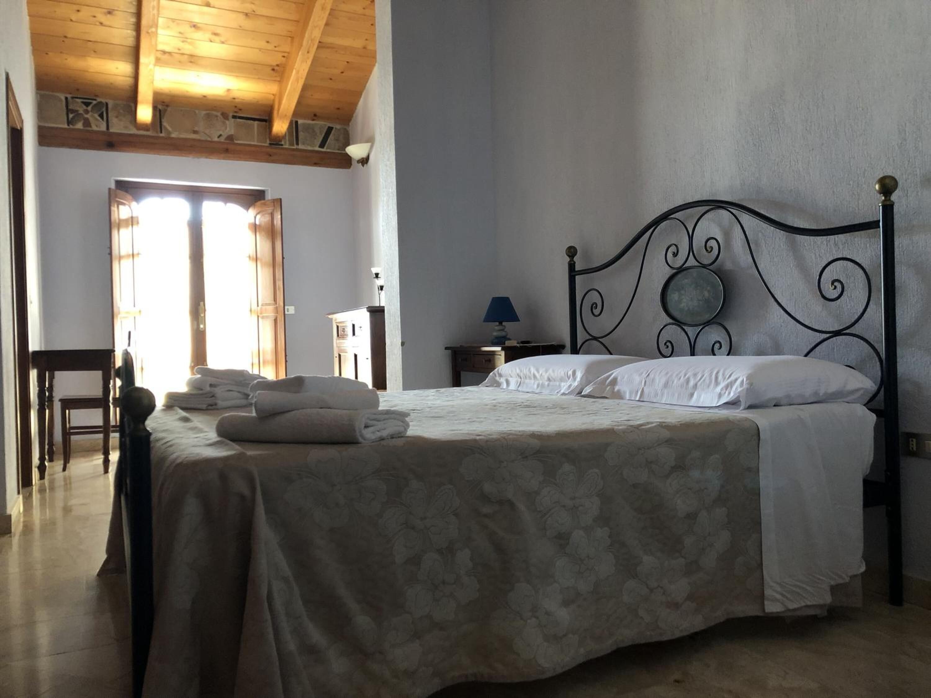 Une chambre à coucher avec un lit, une chaise, une table de chevet et une lampe.