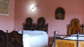 A bedroom with two wooden beds, a stone wall, a wooden ceiling, and a tiled floor.