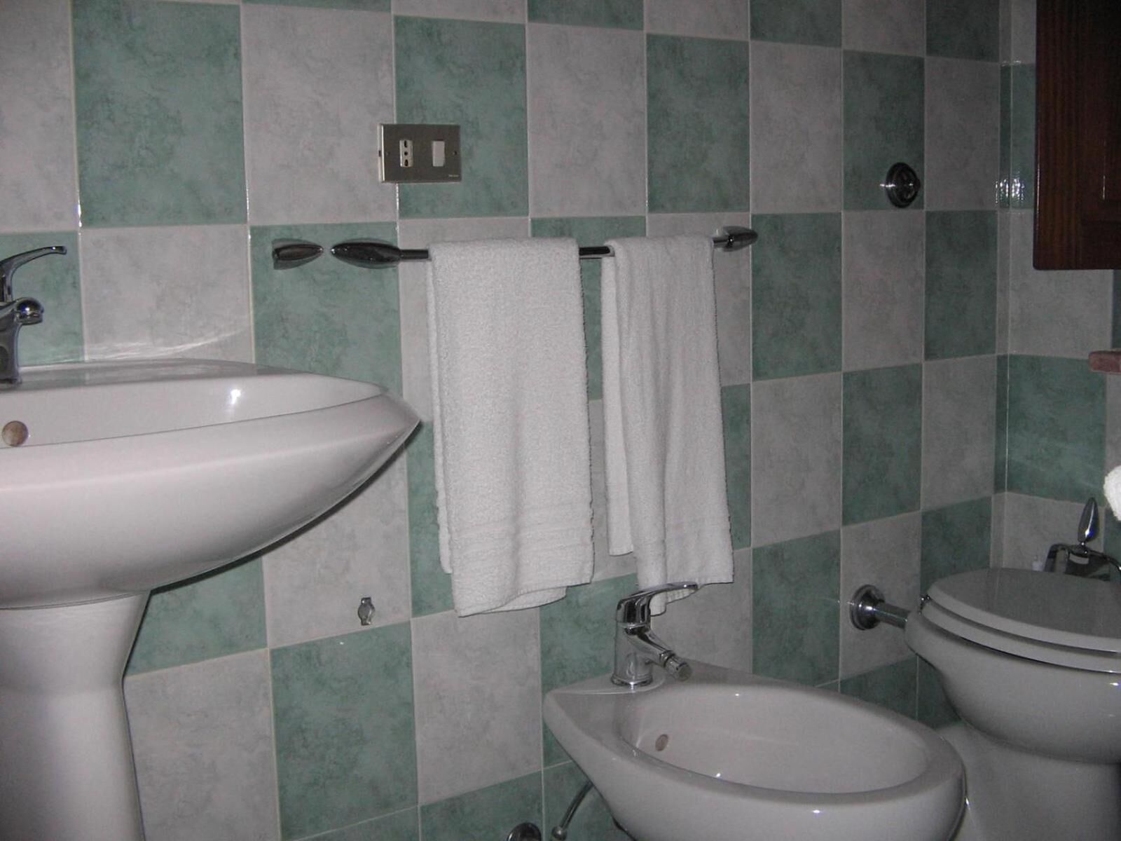 A bathroom with a sink, bidet, and toilet.