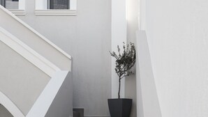 A white building with a staircase and a potted plant. - Pnoi Luxury Suites (Santorini)