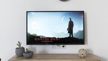 Un televisor montado sobre un mueble de madera con cestas tejidas decorativas en la pared superior.