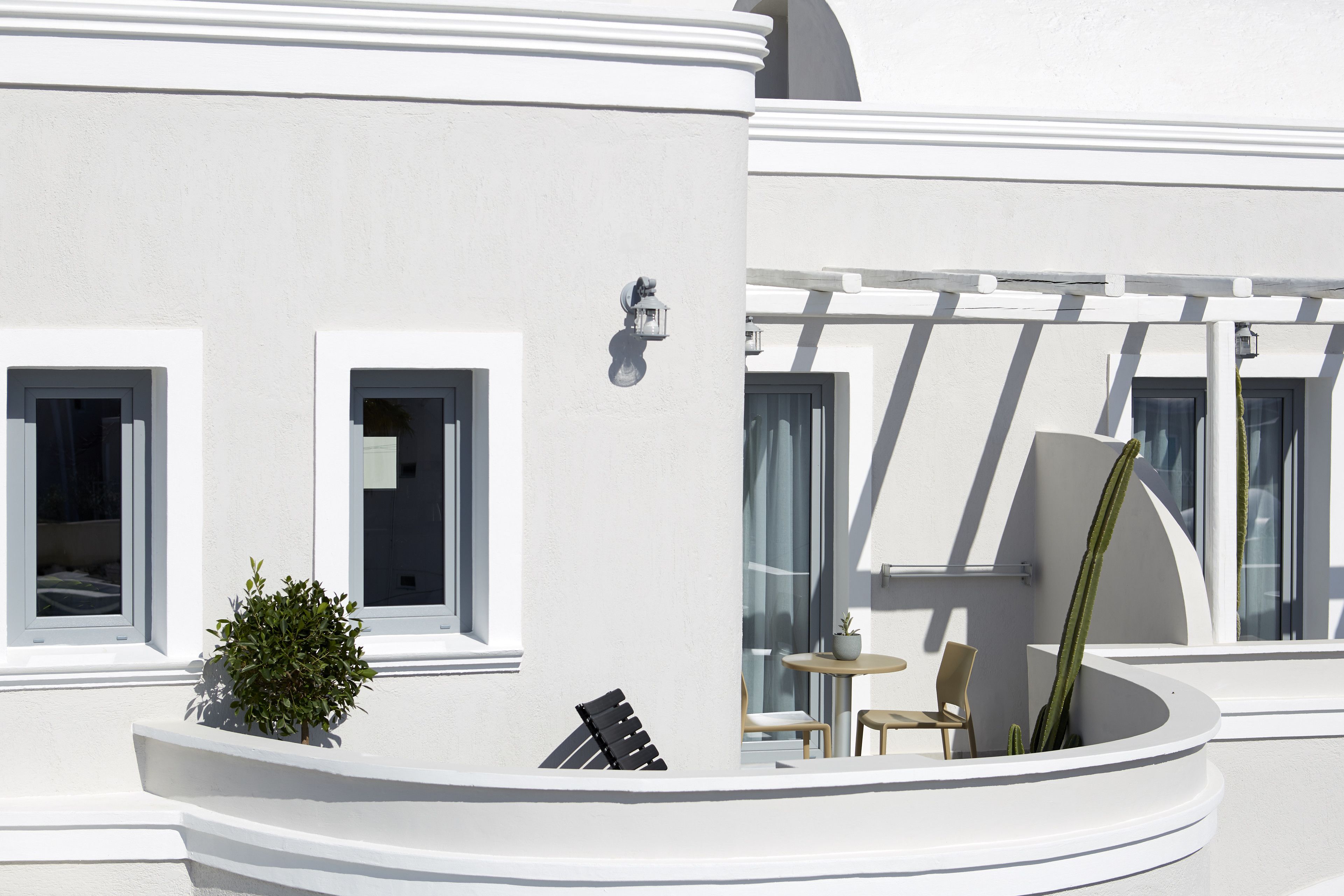 Ein weißes Gebäude mit einem Balkon, einem Tisch, zwei Stühlen und einem Blumentopf.