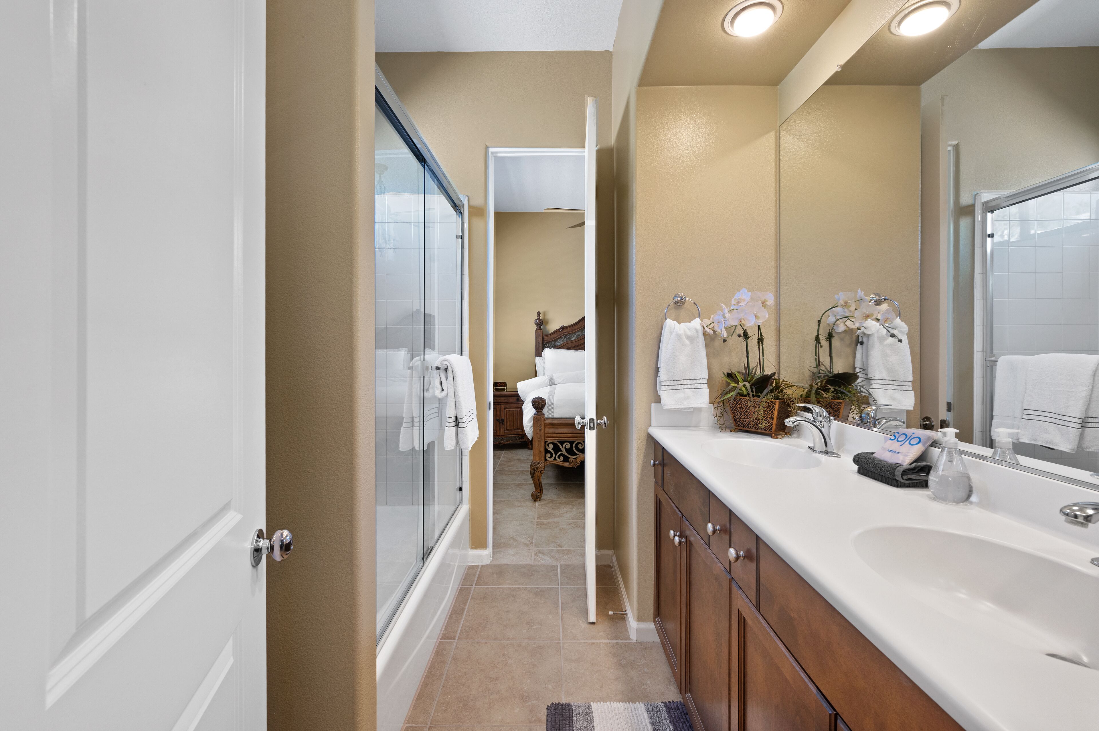 Une salle de bain moderne avec une douche en verre, un grand miroir et un meuble-lavabo doté d’un évier et d’un porte-serviettes.