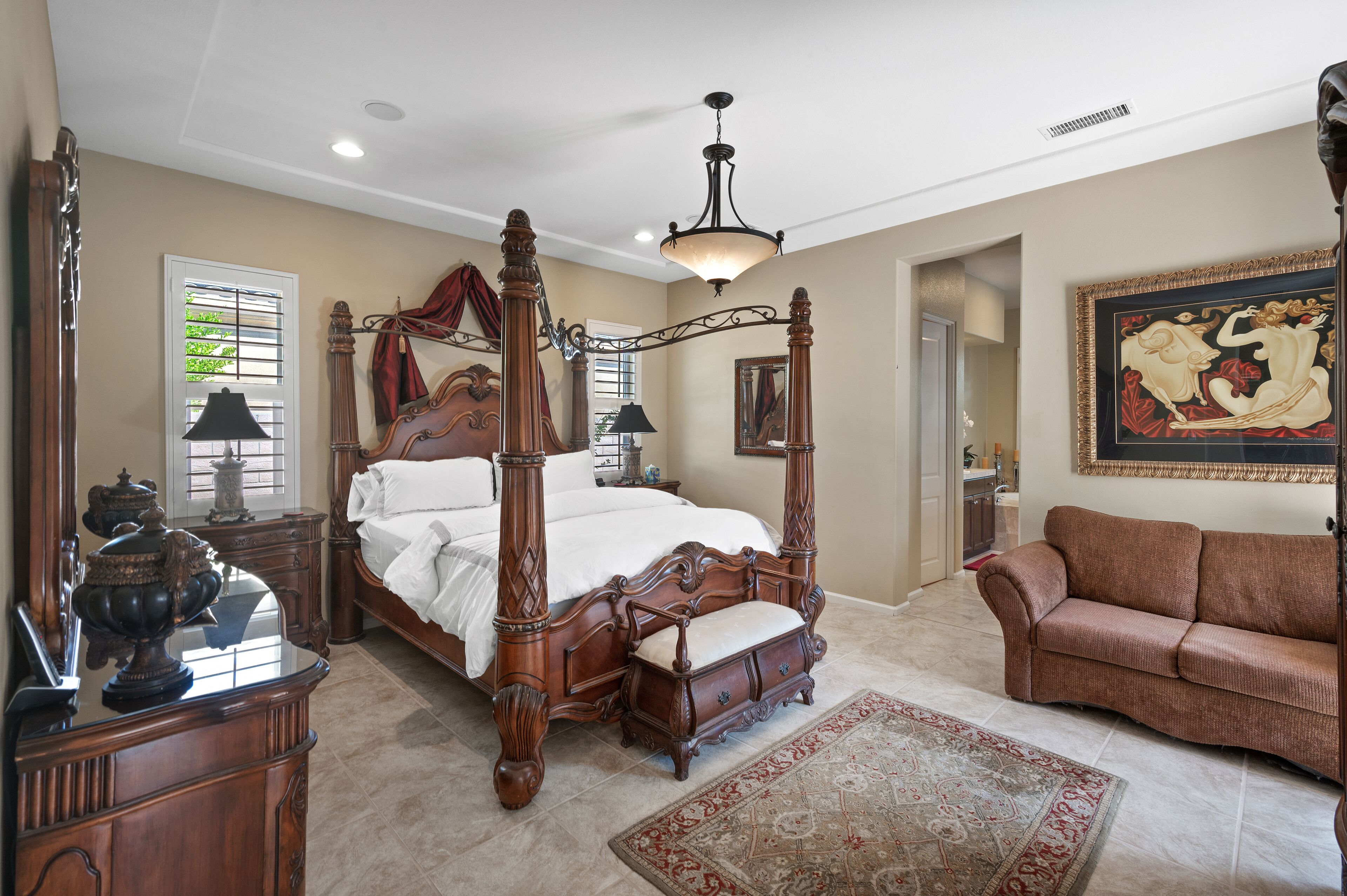 Une chambre spacieuse avec un lit à baldaquin, un grand miroir et un lustre classique.