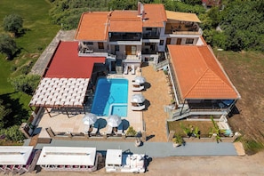 A multi-story building with a swimming pool, outdoor seating, and a covered patio area.