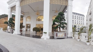 A grand entrance with white columns, a chandelier, and potted plants.