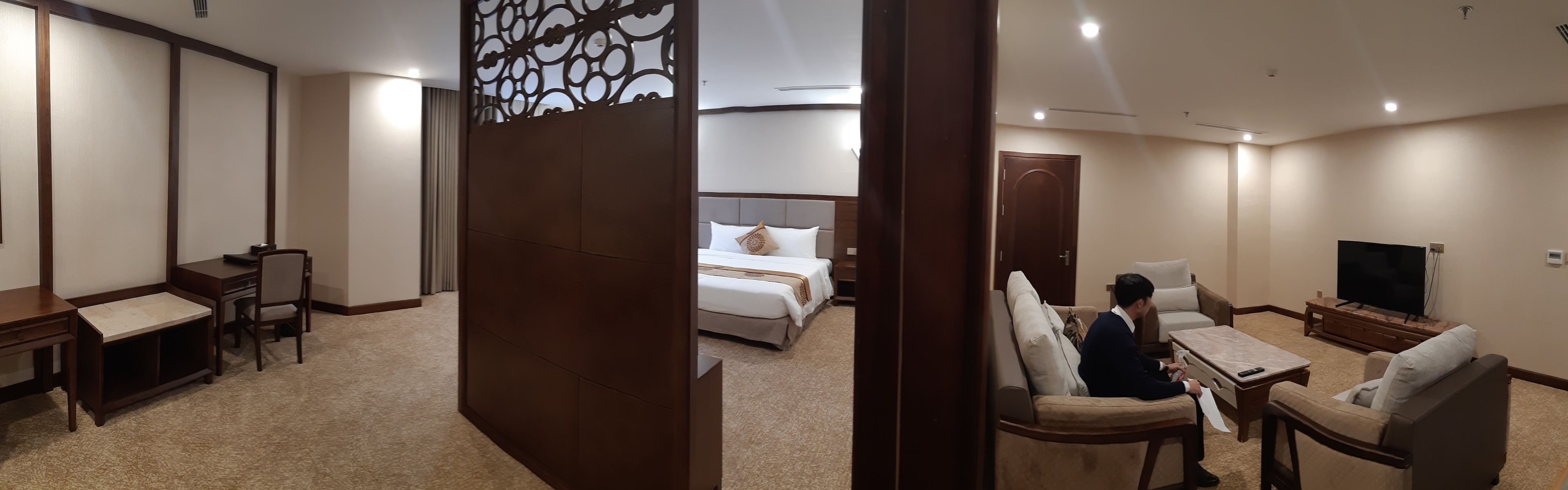 Ein Hotelzimmer mit Bett, Schreibtisch, Stuhl, Fernseher und einer Couch.