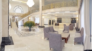 A spacious lobby with a grand staircase, a reception desk, and comfortable seating areas.