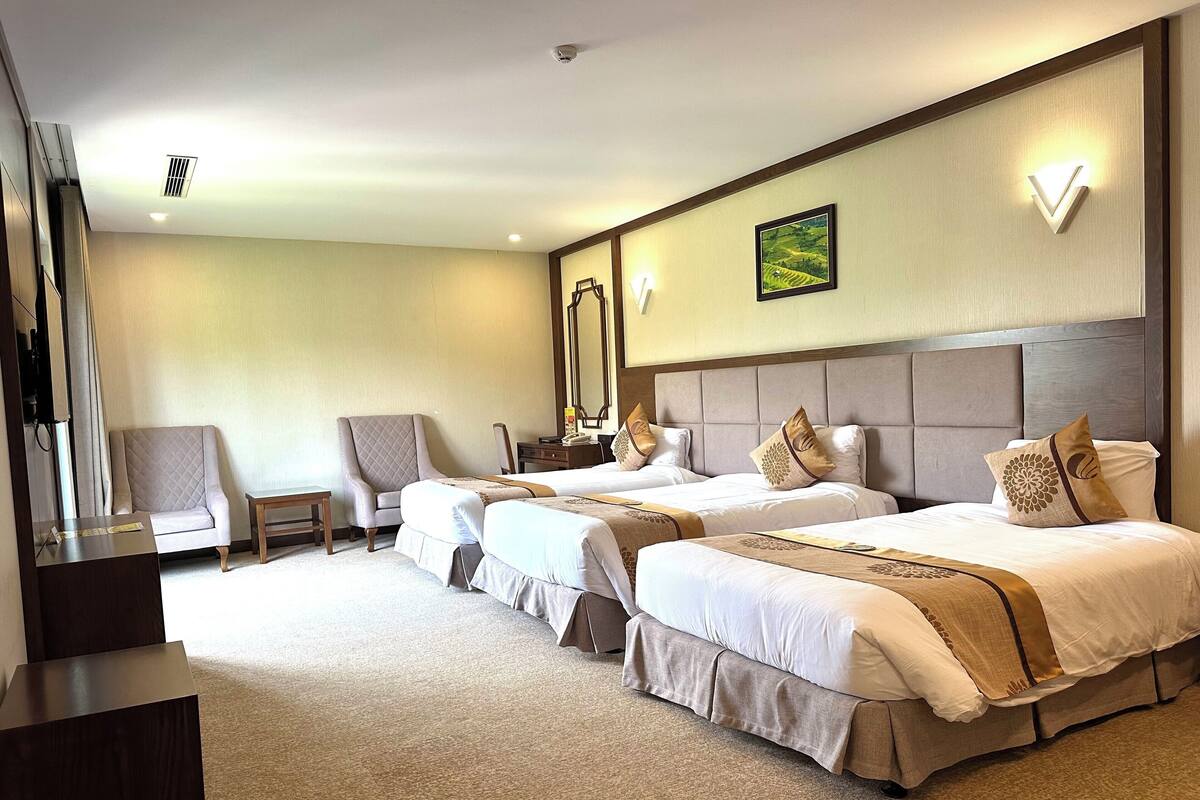A hotel room with two beds, a chair, a desk, and a large mirror.