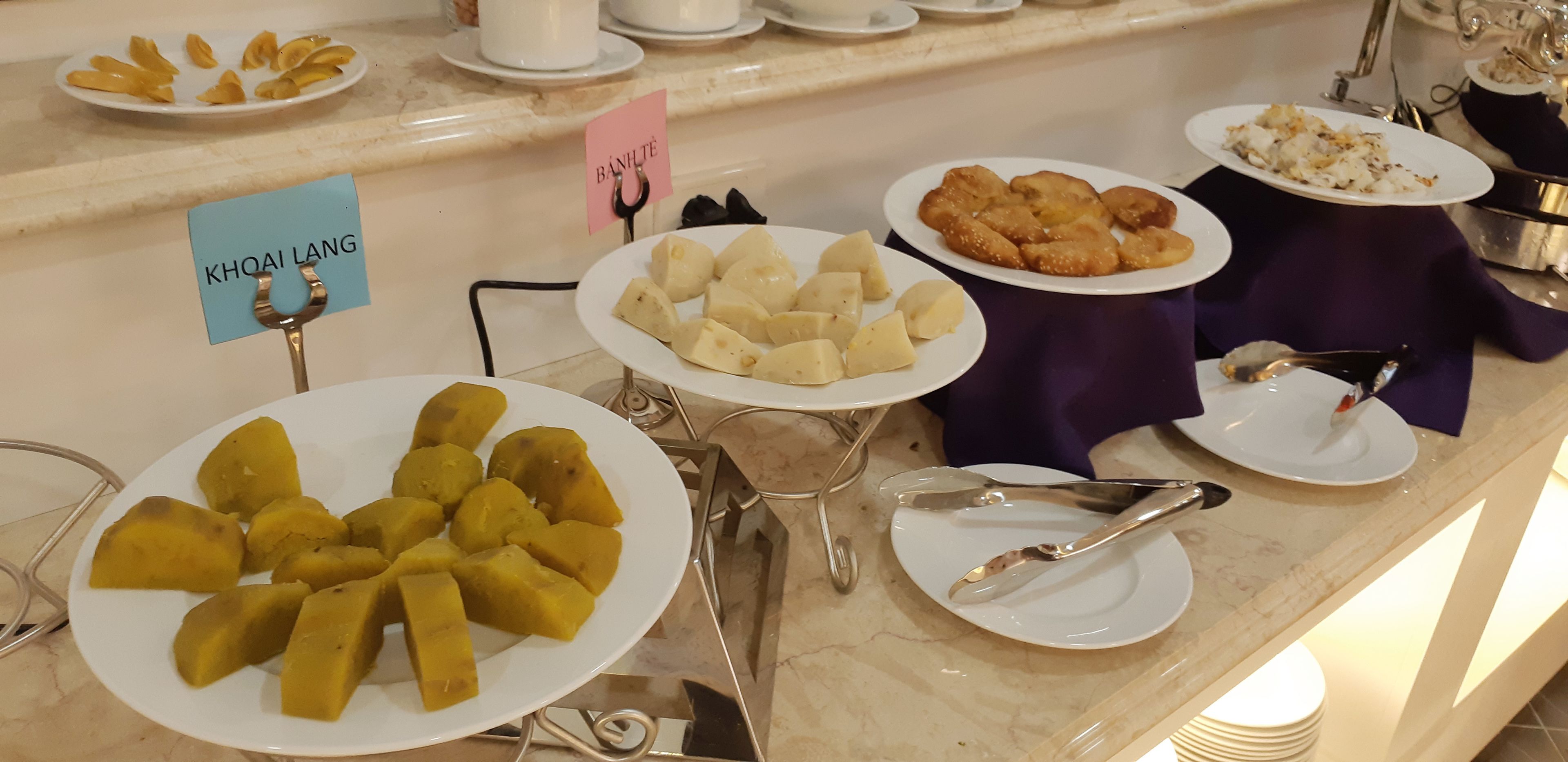 A buffet with various dishes including khqai lang, white cubes, and fried items.