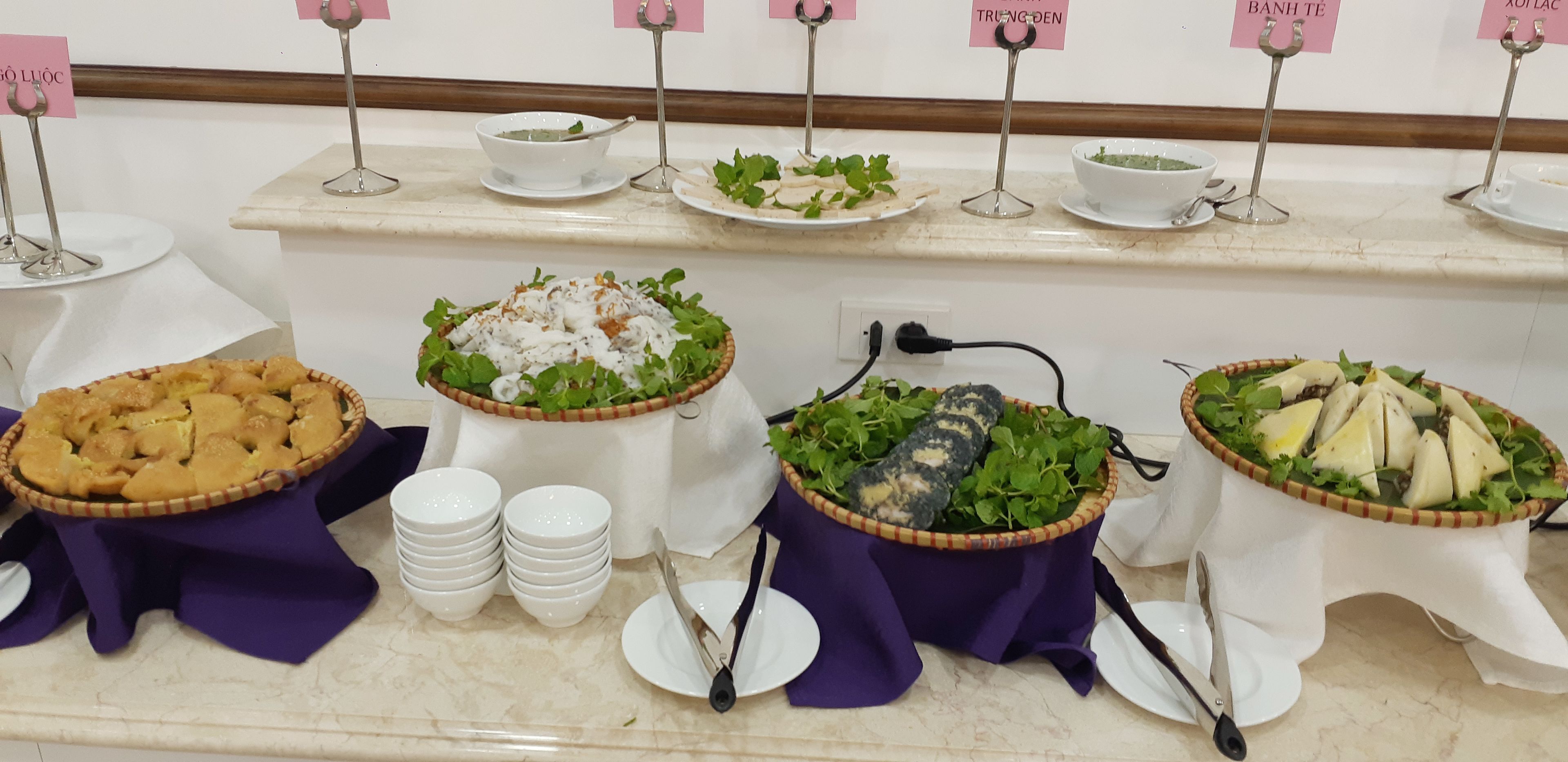 A buffet table with various dishes, including a pie, salads, and a bowl of soup, each labeled with a pink sign.