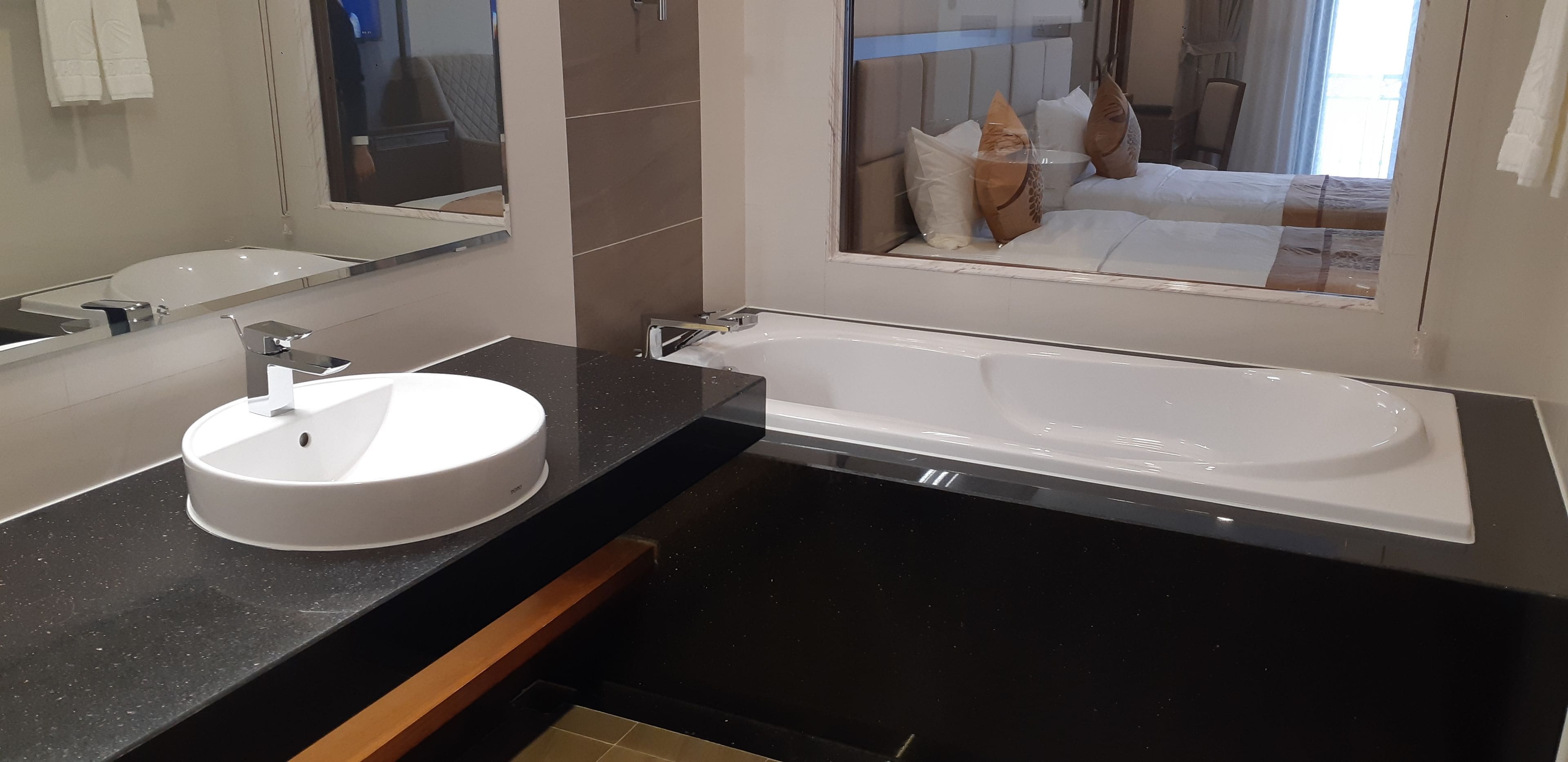 A modern bathroom with a round sink, a large bathtub, and a mirror above the sink.