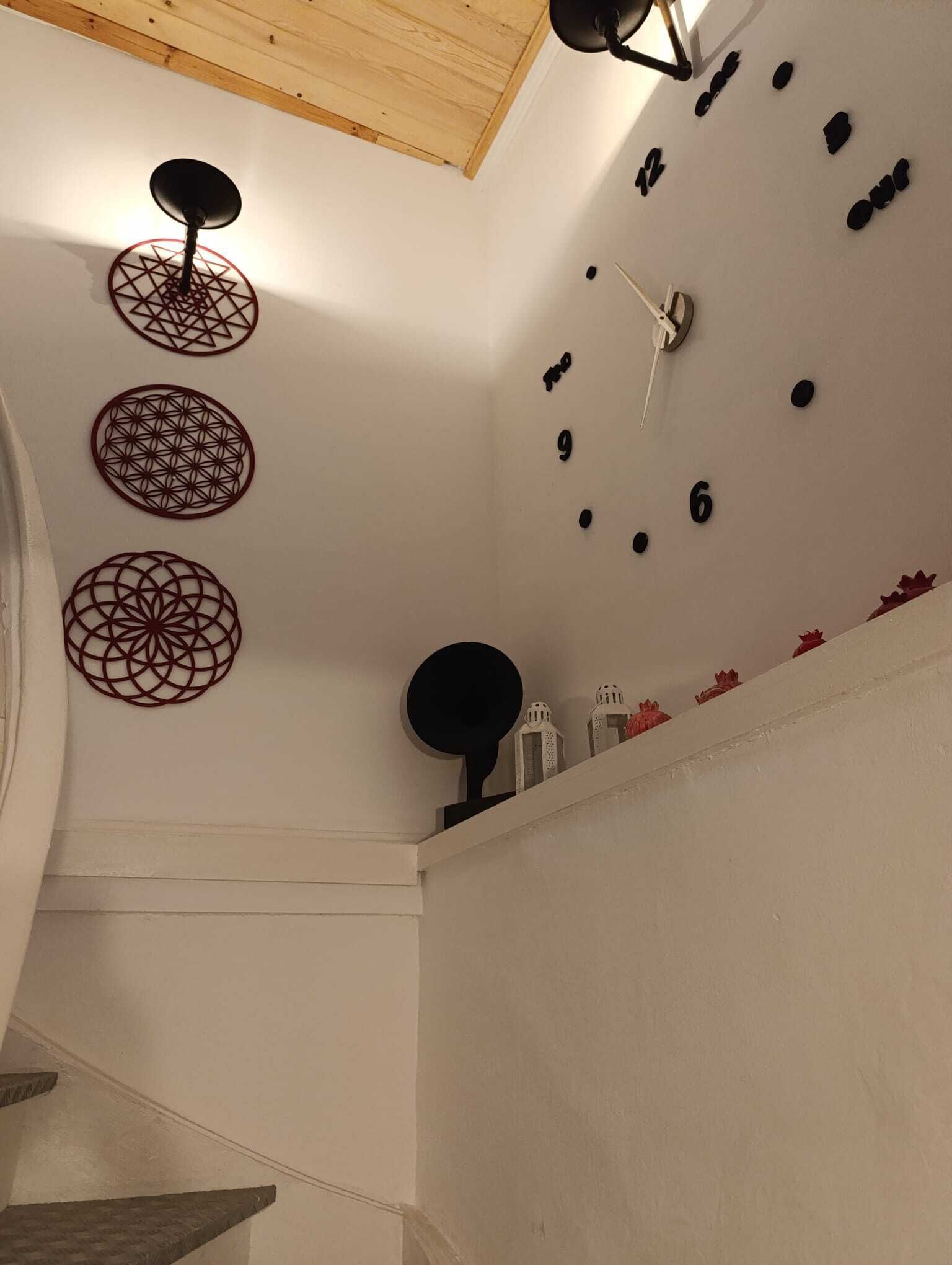Ein Zimmer mit weißer Wand, Holzboden und einer Uhr mit Ziffern und Verzierungen.