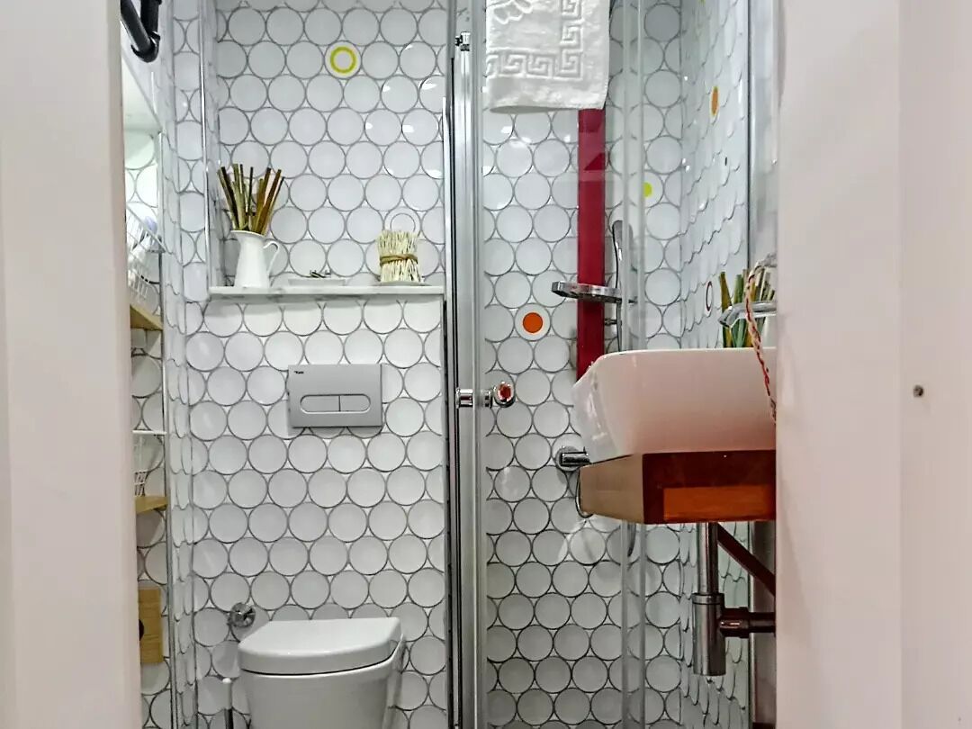 A bathroom with a white toilet, a glass shower enclosure, and a sink with a pink basin.