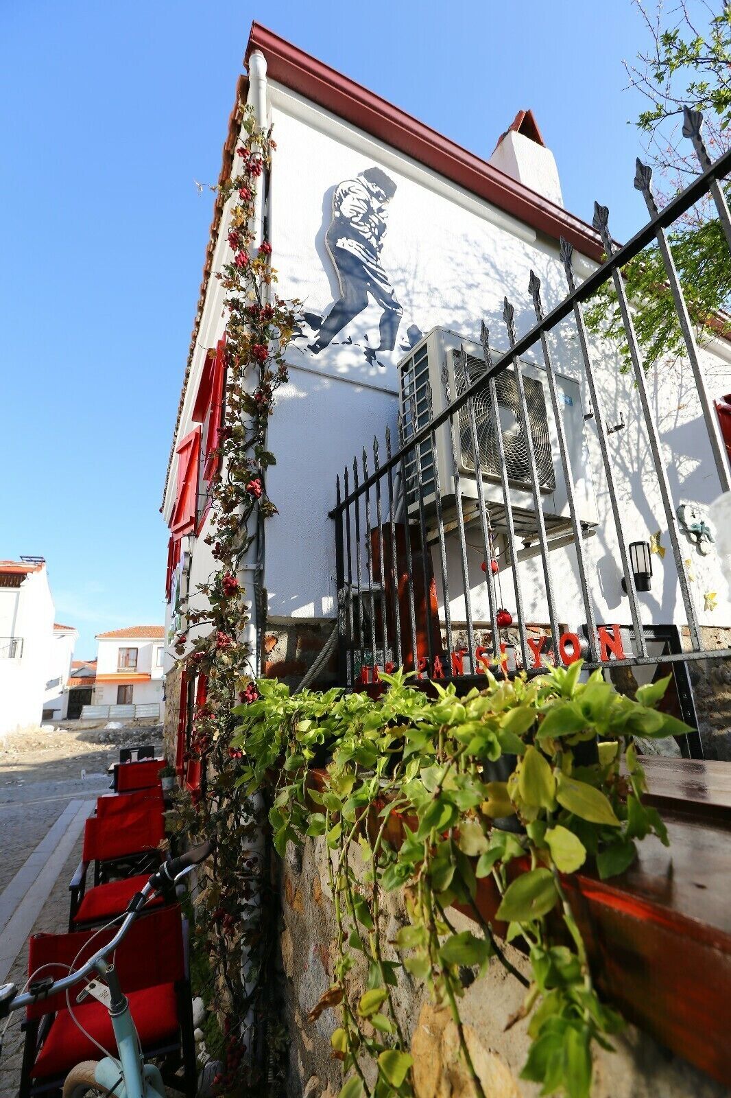 A building with a mural, red shutters, and a metal fence.