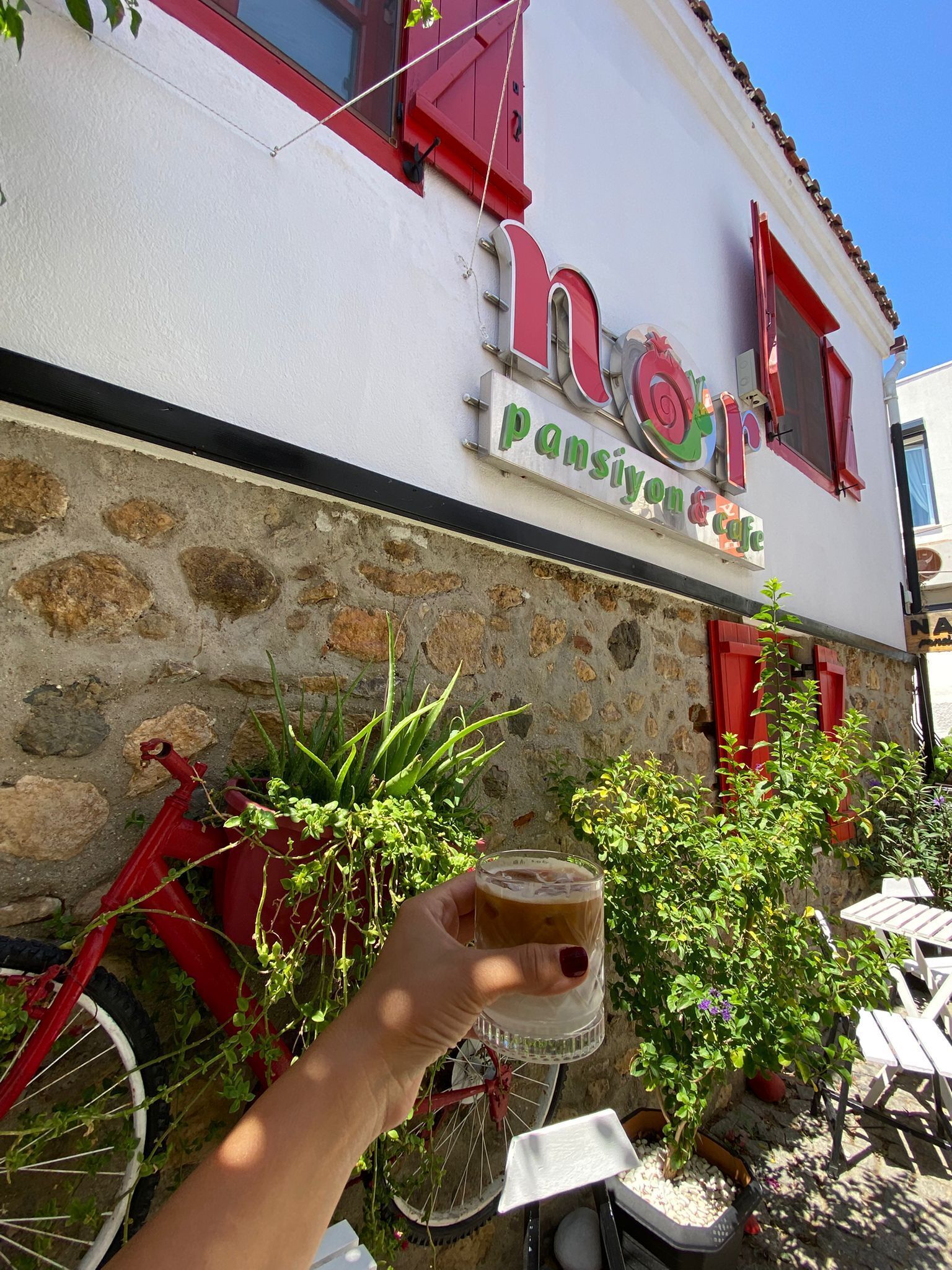 A building with a sign that reads 'nansiyon cafe' and a bicycle parked in front.