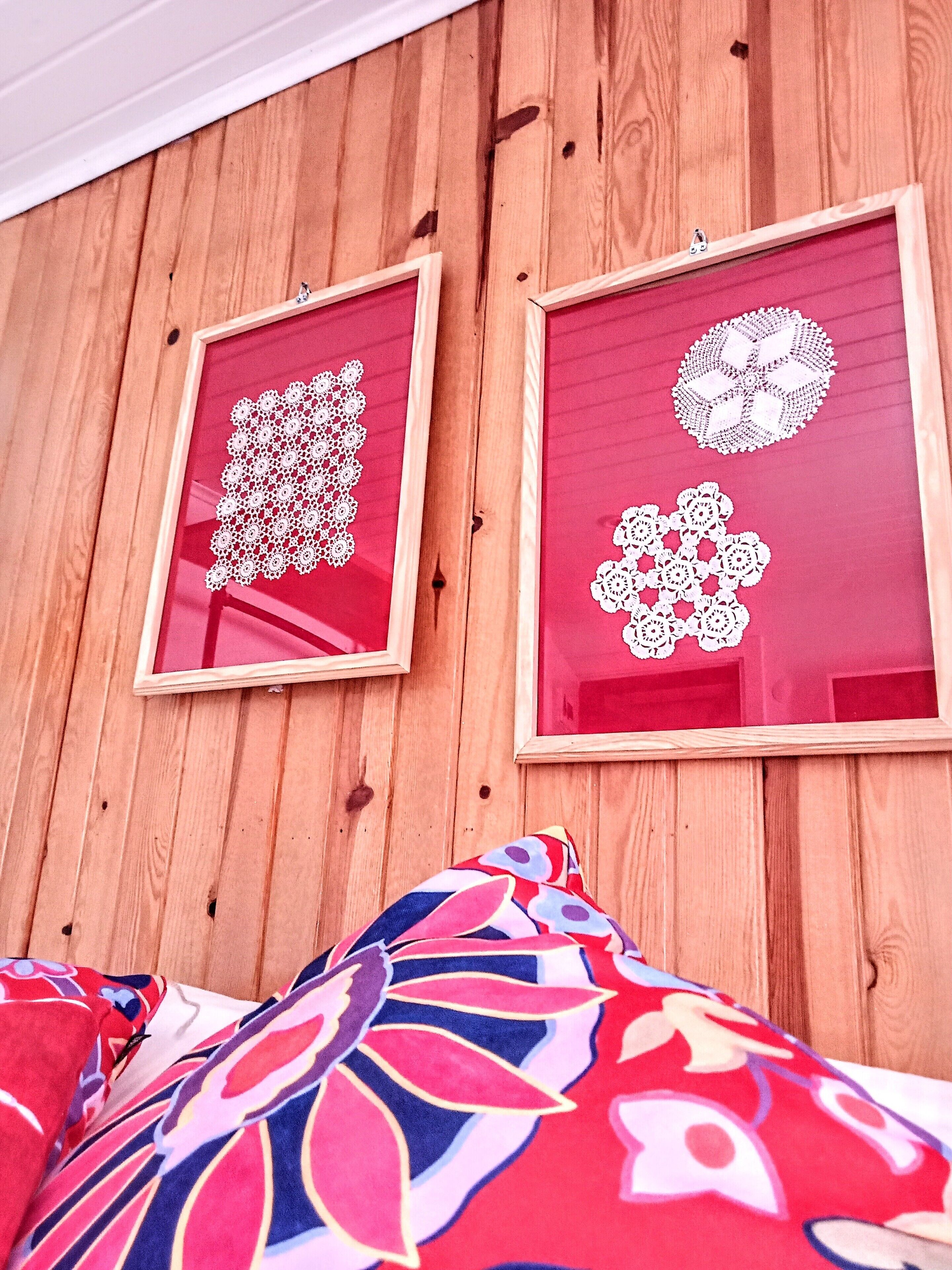Two framed crochet patterns on a wooden wall.