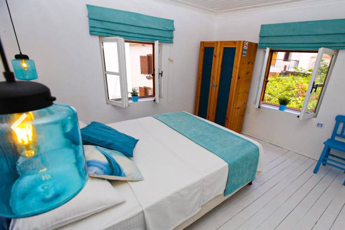 Quarto com cama, cadeira, guarda-roupa e janela com cortinas.