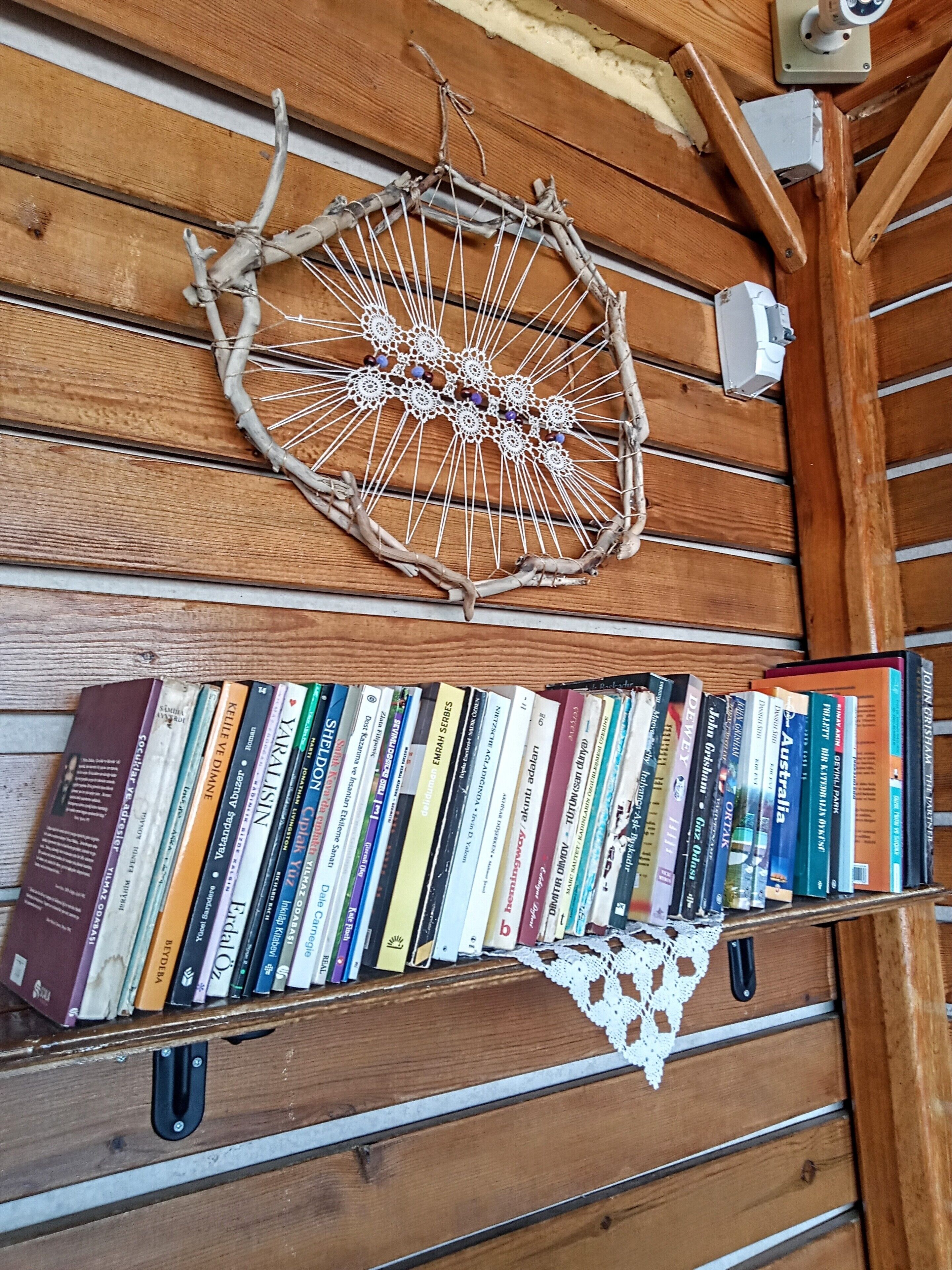 A wooden bookshelf with a decorative woven item and a collection of books.