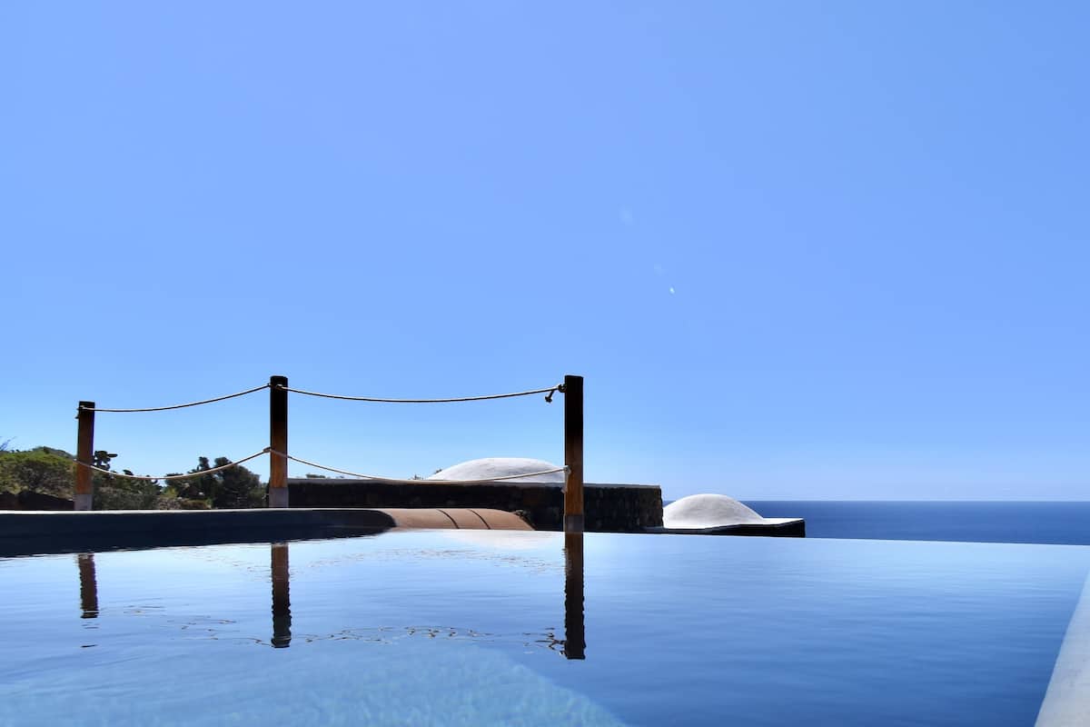 An infinity pool with a clear view of the ocean and a rope barrier.