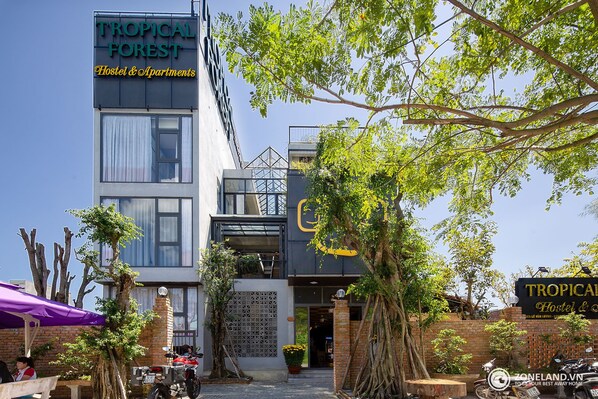 Um edifício moderno com uma placa que diz "TROPICAL FOREST Hostel & Apartments".