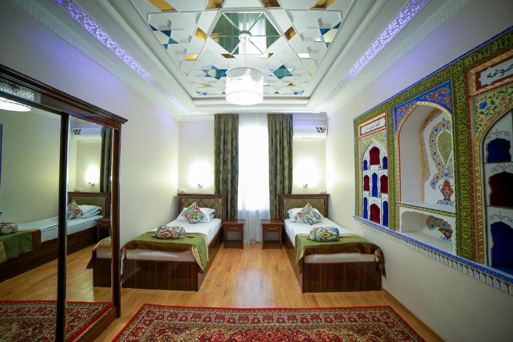 A hotel room with two beds, a large mirror, a chandelier, and decorative wall art.