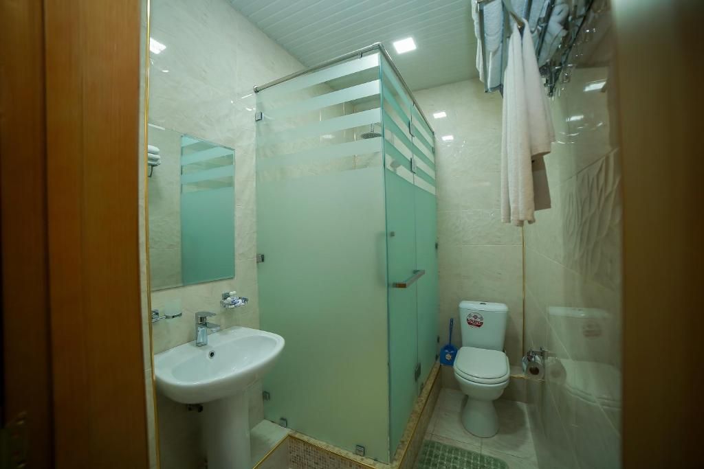 A bathroom with a glass shower enclosure, a sink, and a toilet.