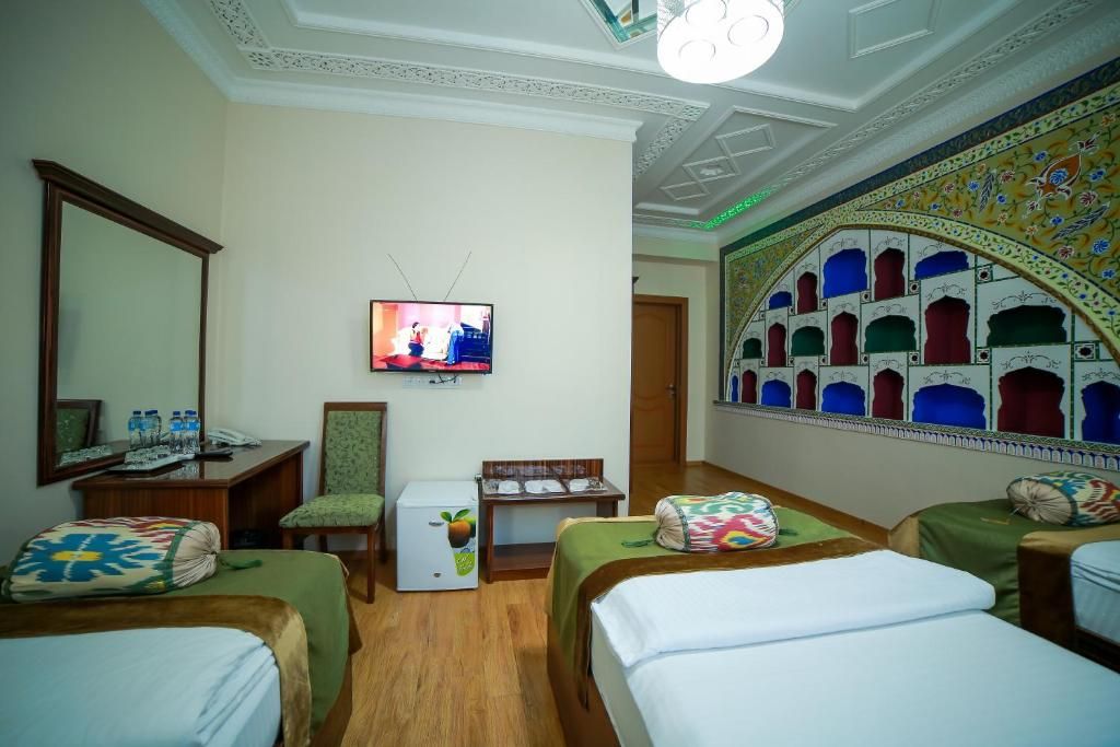 A hotel room with two beds, a television, a desk with a chair, and a decorative wall.