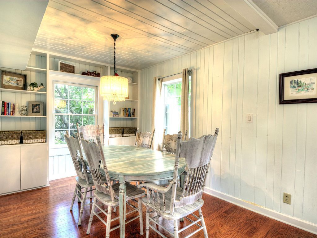 A dining room with a wooden table and chairs, built-in shelves, and a chandelier.