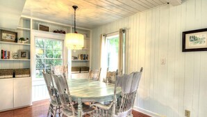 Comedor con mesa y sillas de madera, estanterías empotradas y una araña.