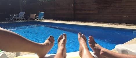 A swimming pool with two people relaxing on the edge.