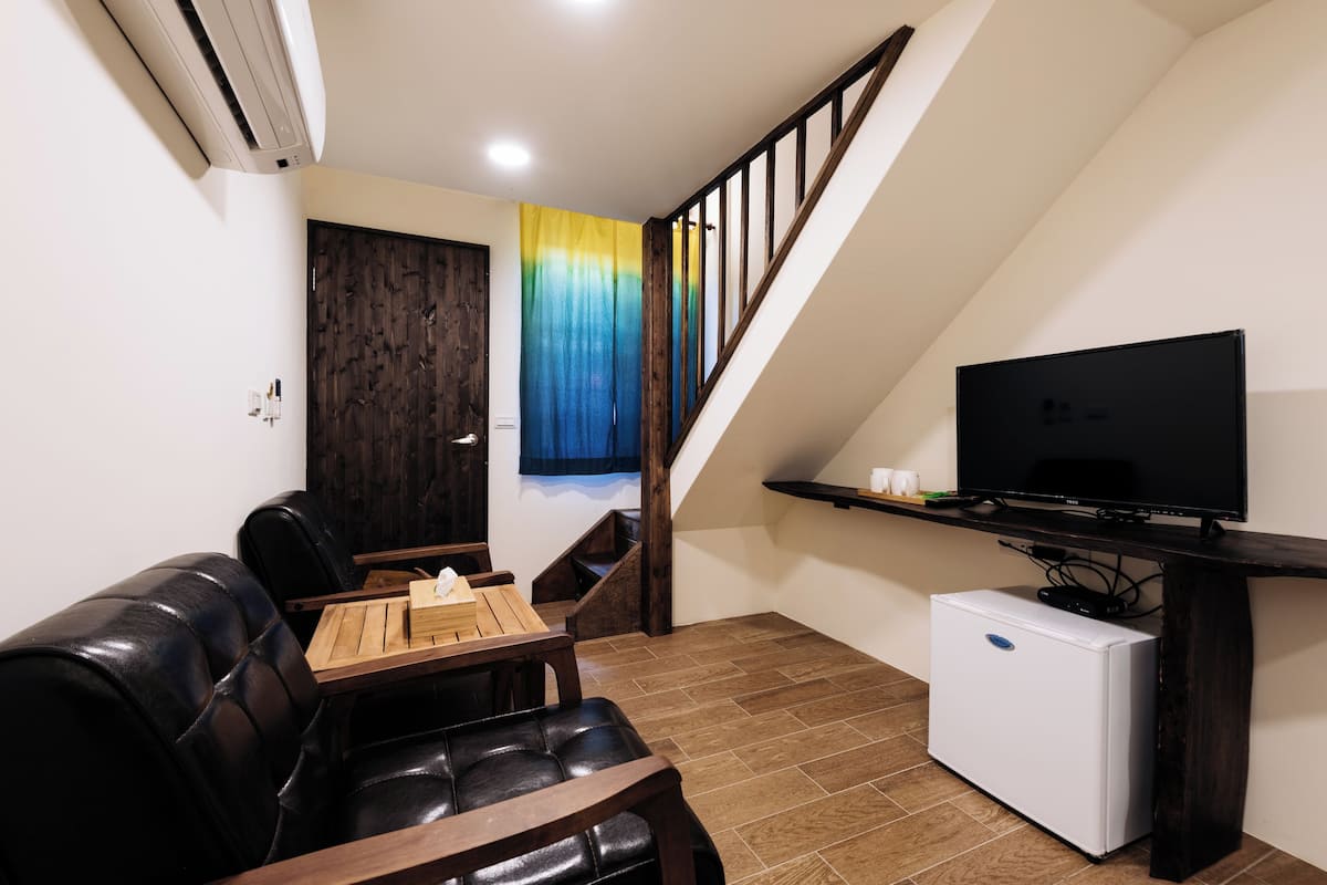 A living room with a sofa, a coffee table, a TV, and a small refrigerator.