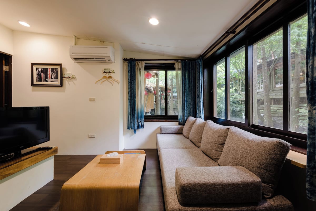 A modern living room with a flat-screen TV, a wooden coffee table, and a large sofa.