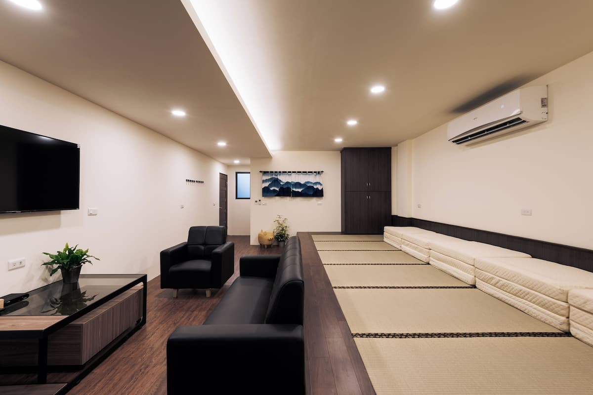 A modern waiting area with a sofa, chairs, a flat-screen TV, and a wall-mounted air conditioner.