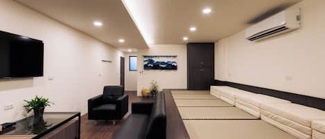 A modern waiting area with a sofa, chairs, a flat-screen TV, and a wall-mounted air conditioner.