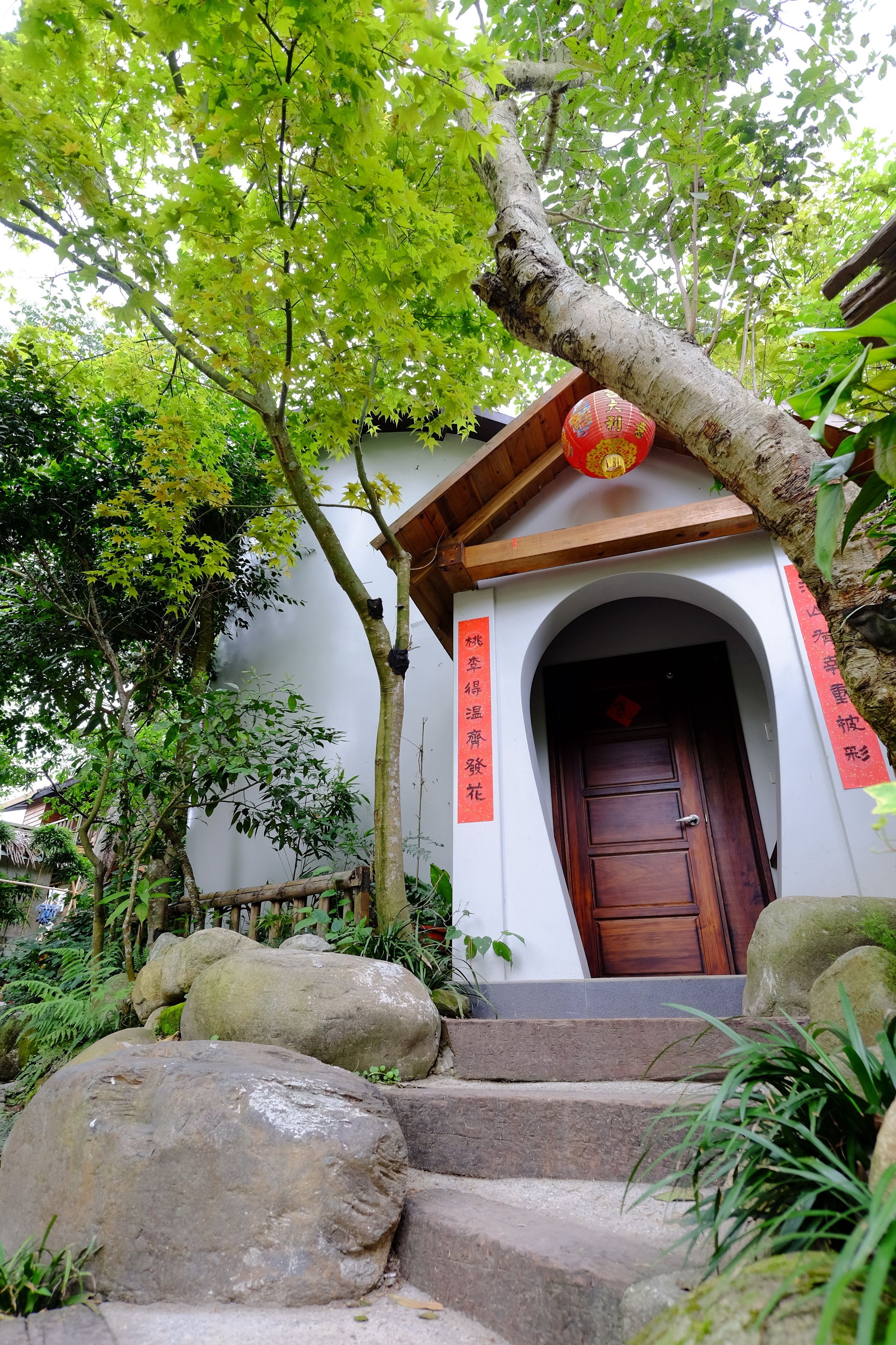 A traditional building with a wooden door, stone steps, and red banners.