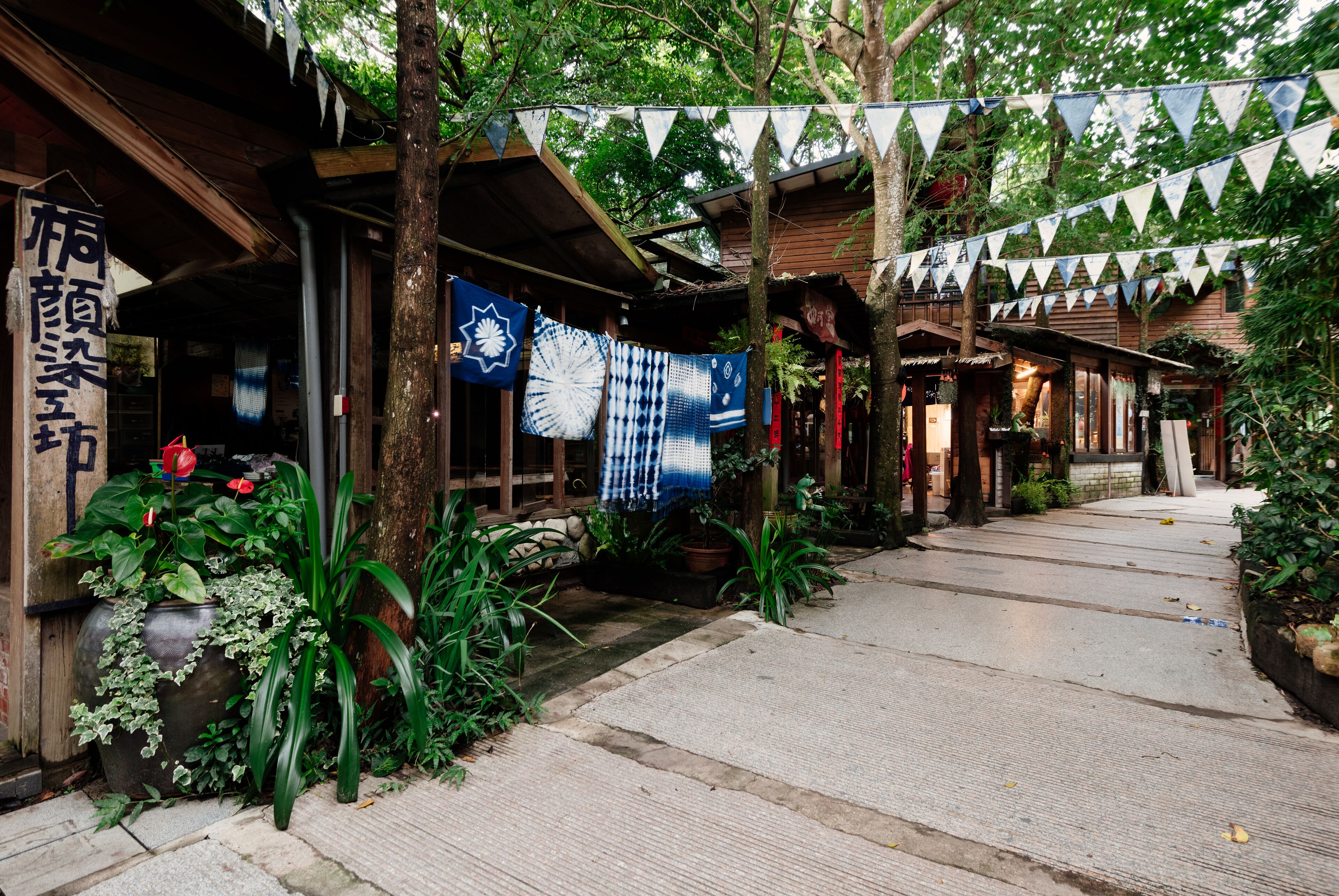 A traditional Japanese building with a covered walkway, potted plants, and hanging decorations.