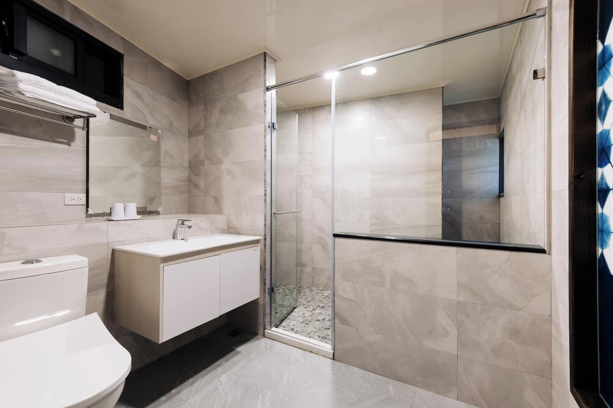 A modern bathroom with a glass-enclosed shower, a white sink, and a toilet.