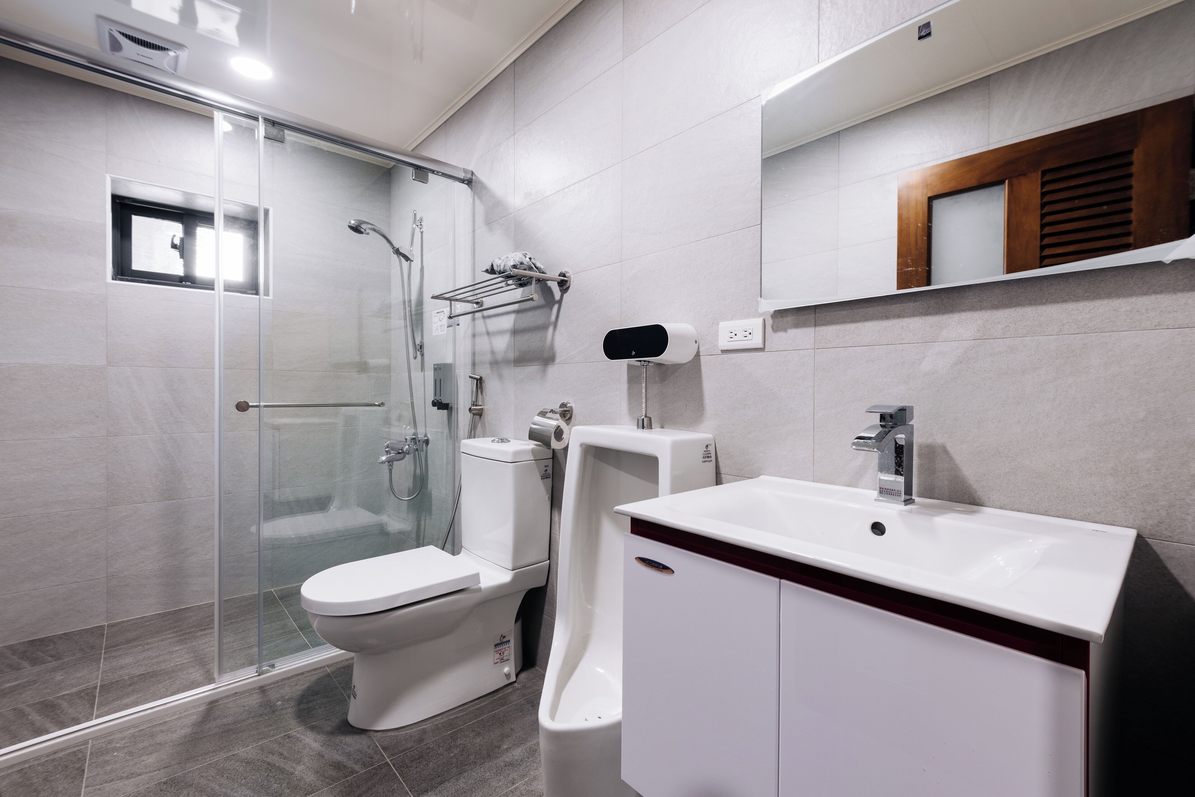 A modern bathroom with a glass-enclosed shower, a toilet, and a sink with a mirror above it.
